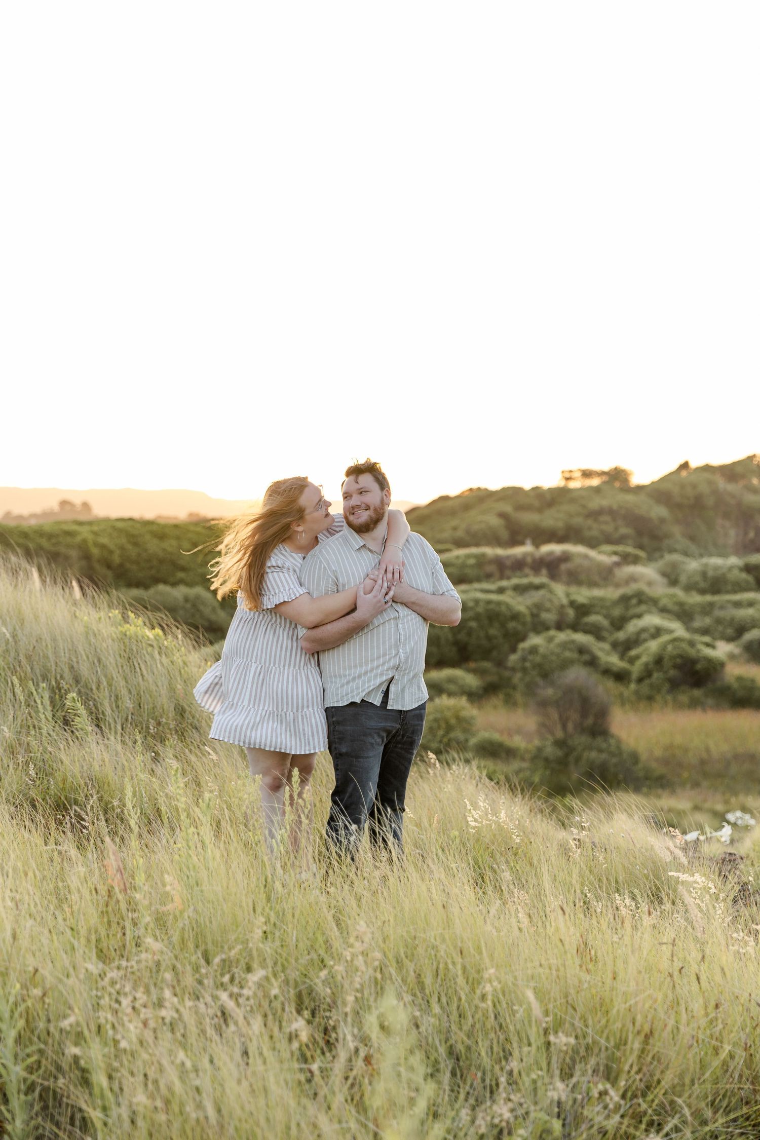 Engaged couple at Bombo Headlands with cliffs and ocean at sunset