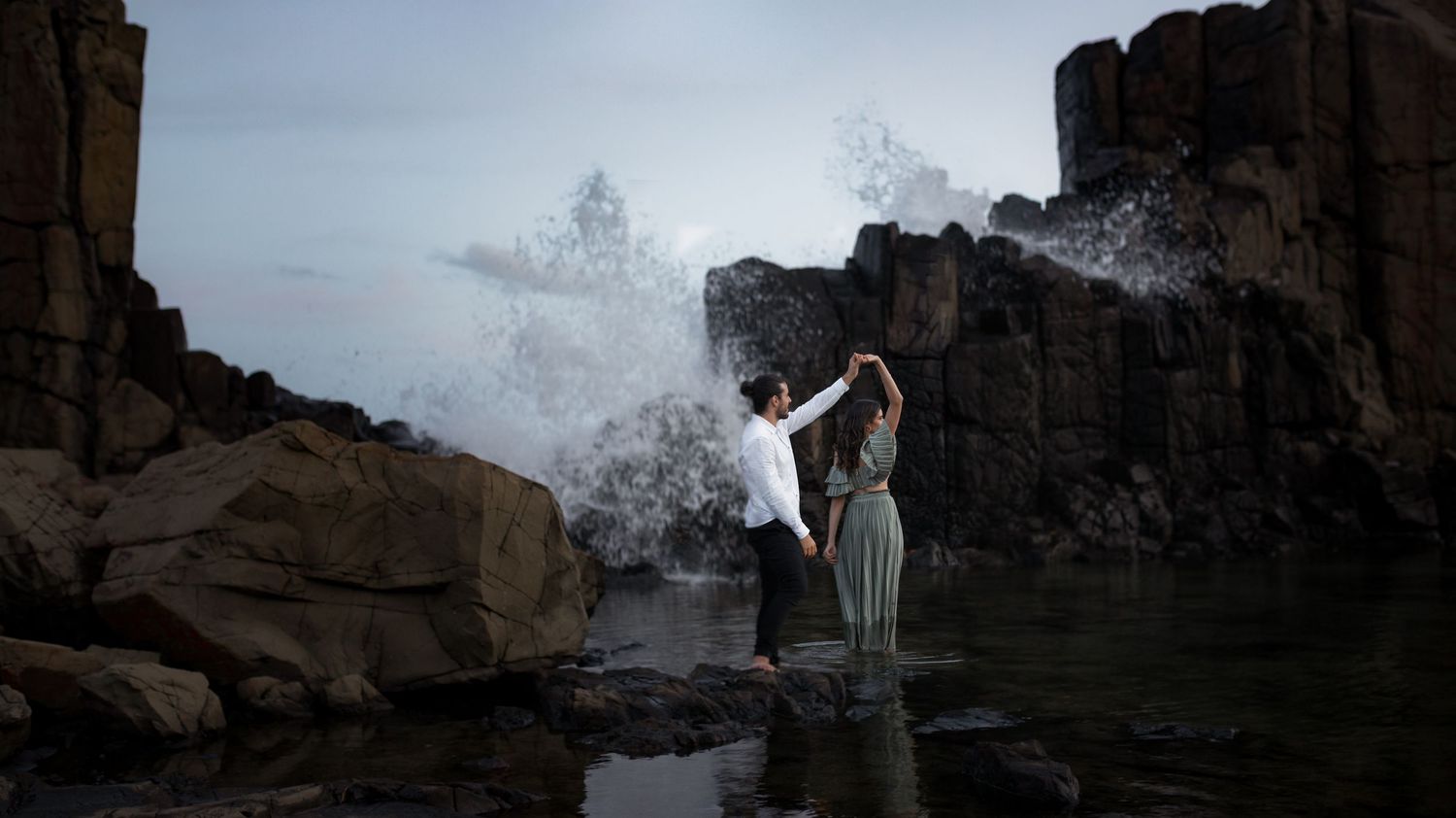 Engaged couple at Bombo Headlands with cliffs and ocean at sunset