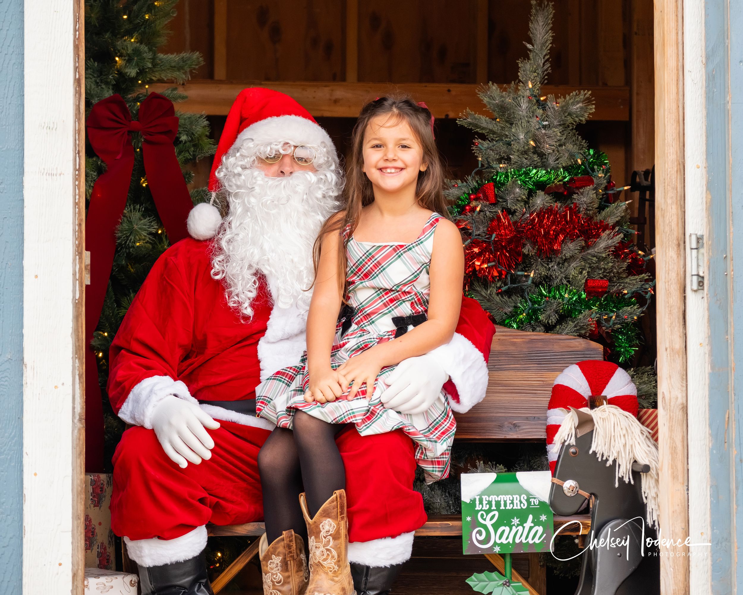 Smiling young girl sitting with Santa Claus at a Christmas photo session at American Made Miniatures photo session in Petaluma, California