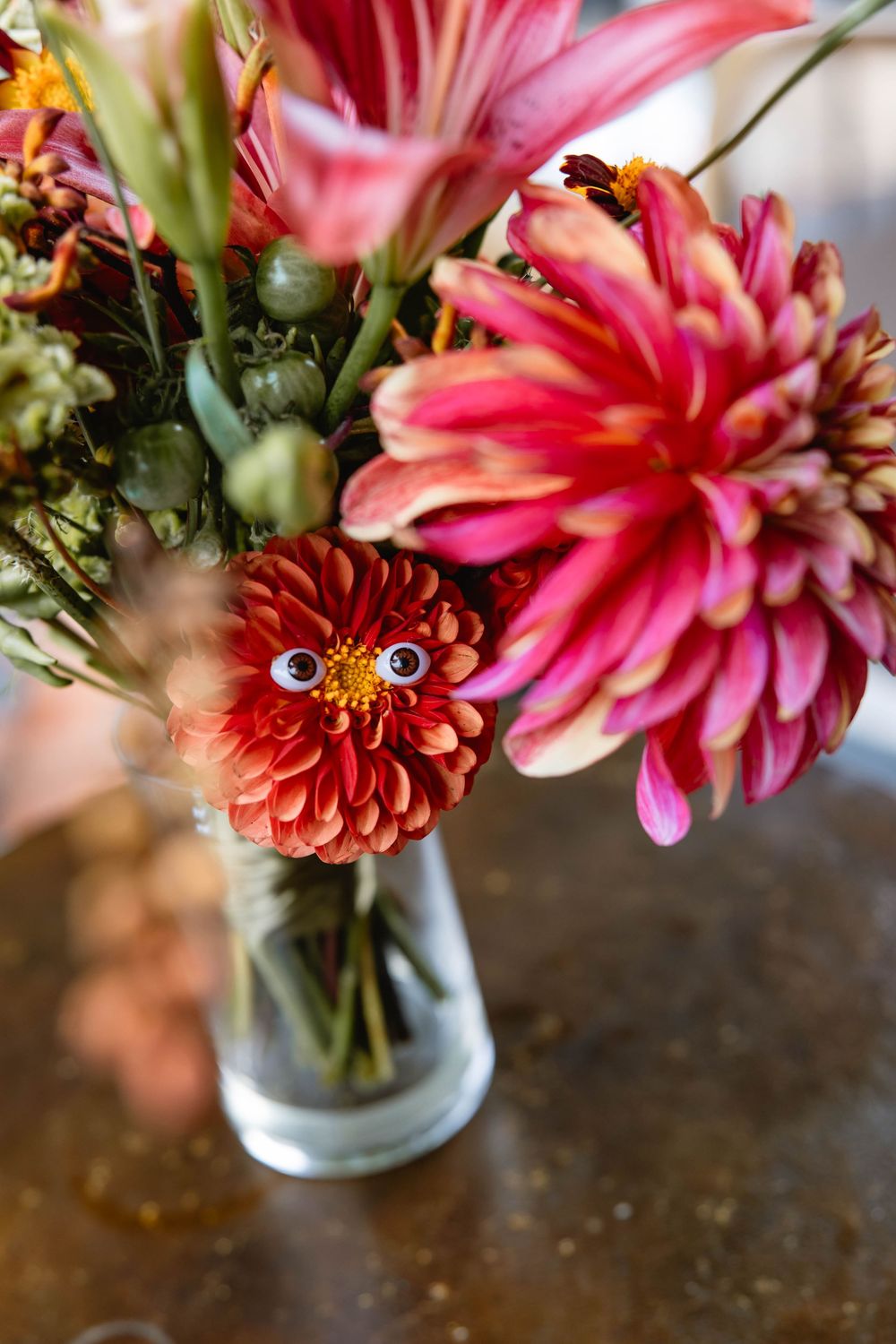 Close-up of pink and coral dahlias and lilies arranged in glass vases. Pizzeria Beddia Wedding. Fishtown Philadelphia, PA.