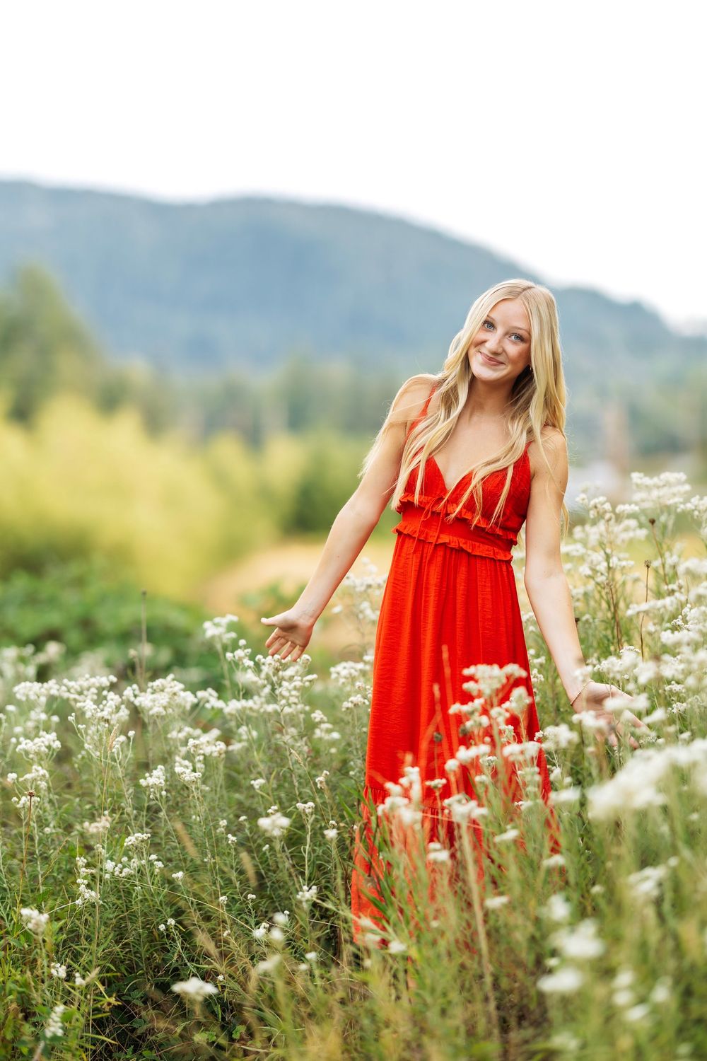 Person in flowing red dress dancing through field of white wildflowers.