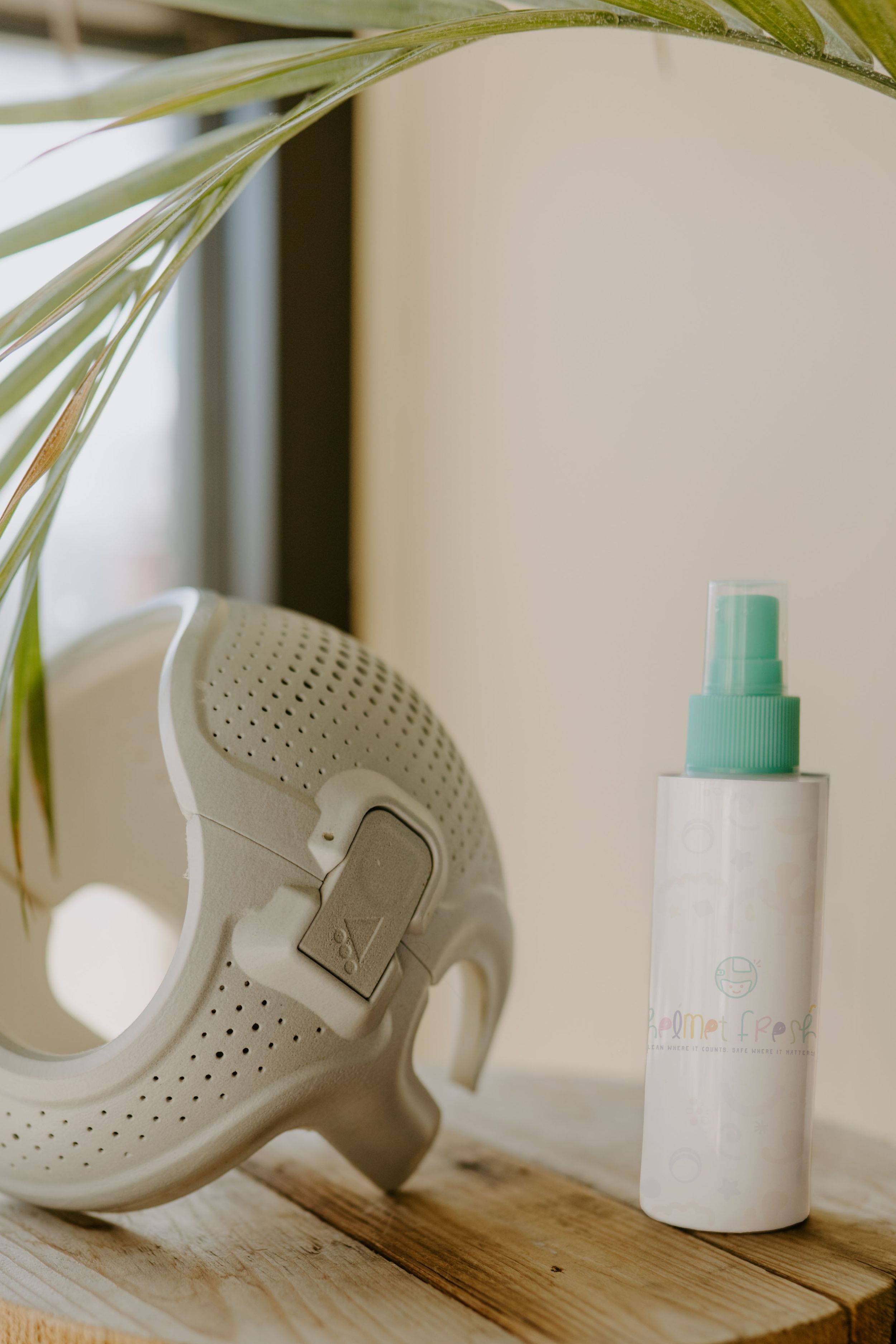 White minimalist bathroom decor with skincare products and palm leaves on wooden shelf.