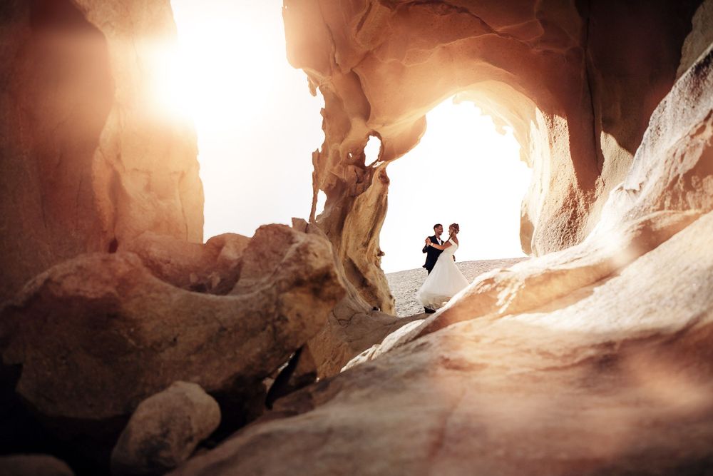 Wedding couple dancing under the natural stone arch at Arco de las Peñitas, Fuerteventura - Photography by photoFuerte