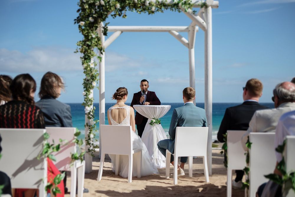 A romantic wedding ceremony under a white wooden altar overlooking the turquoise ocean - Wedding photographer in Fuerteventura