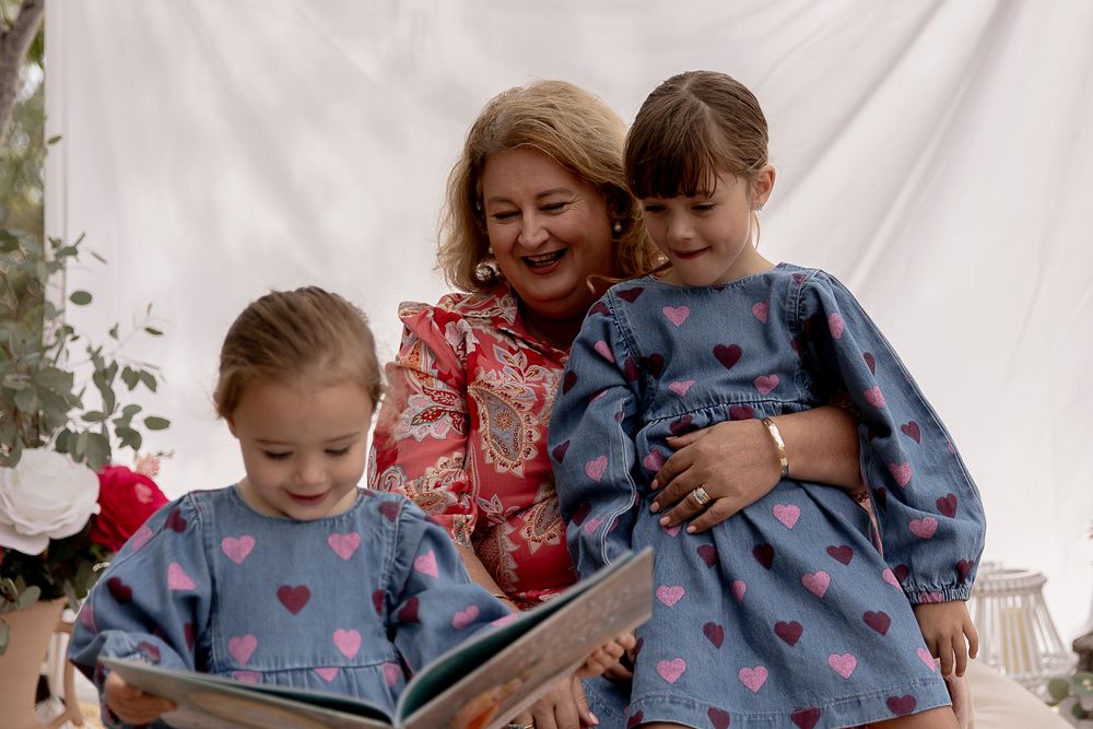 Grandmother reading books to grand daughters during a professional family photo shoot.