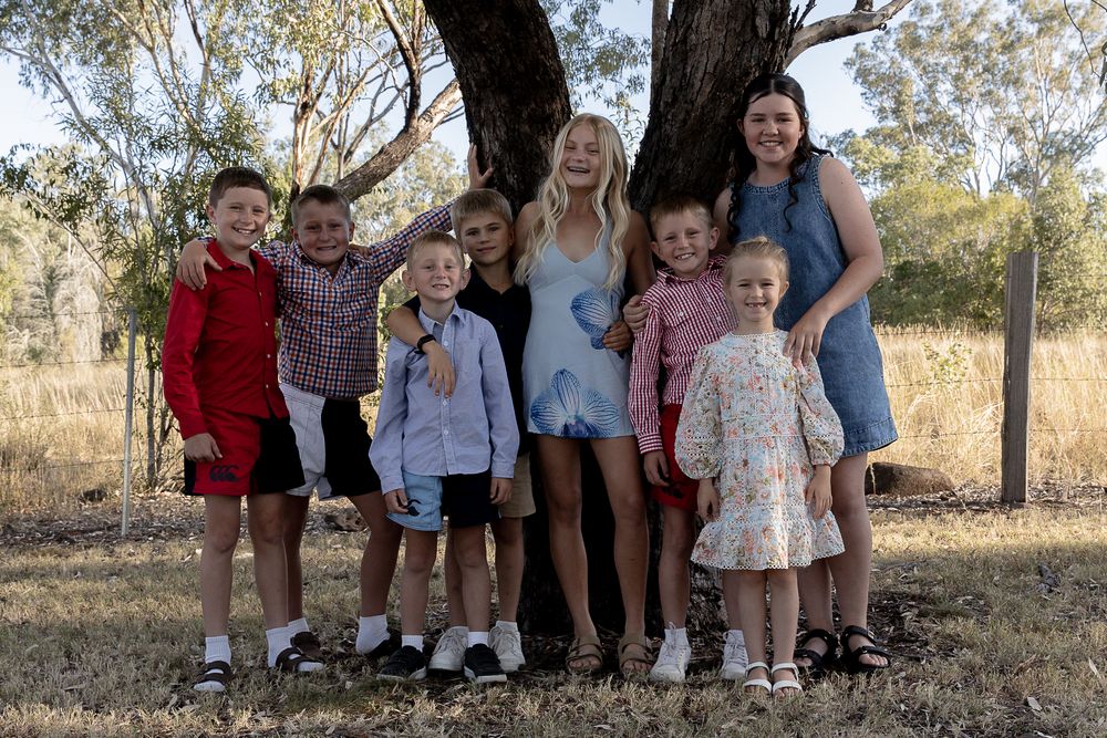 a group of children who are cousins standing beside a tree during a professional family photo shoot.