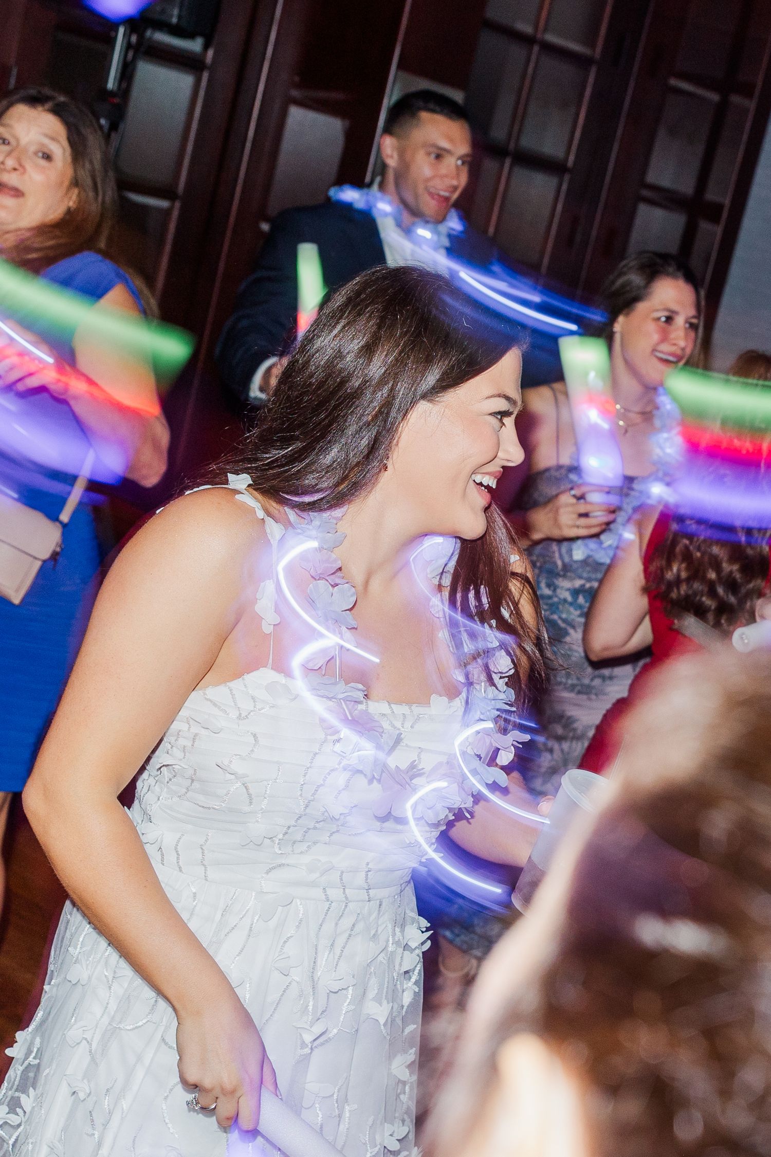 People dancing at a party with colorful light trails and motion blur effects creating a dynamic nightclub atmosphere.