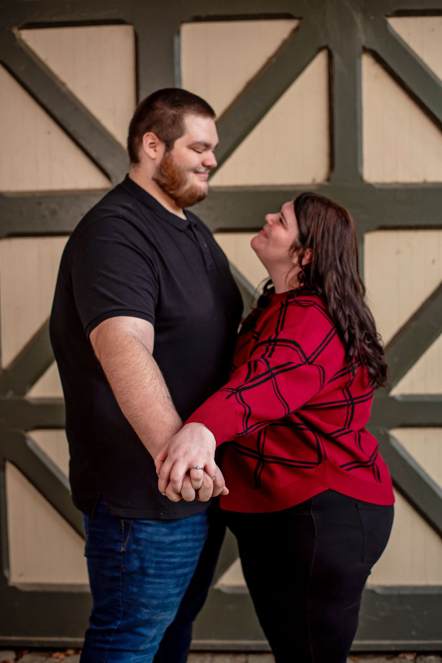 A couple in black and red outfits share an intimate dance pose against a geometric patterned wall.