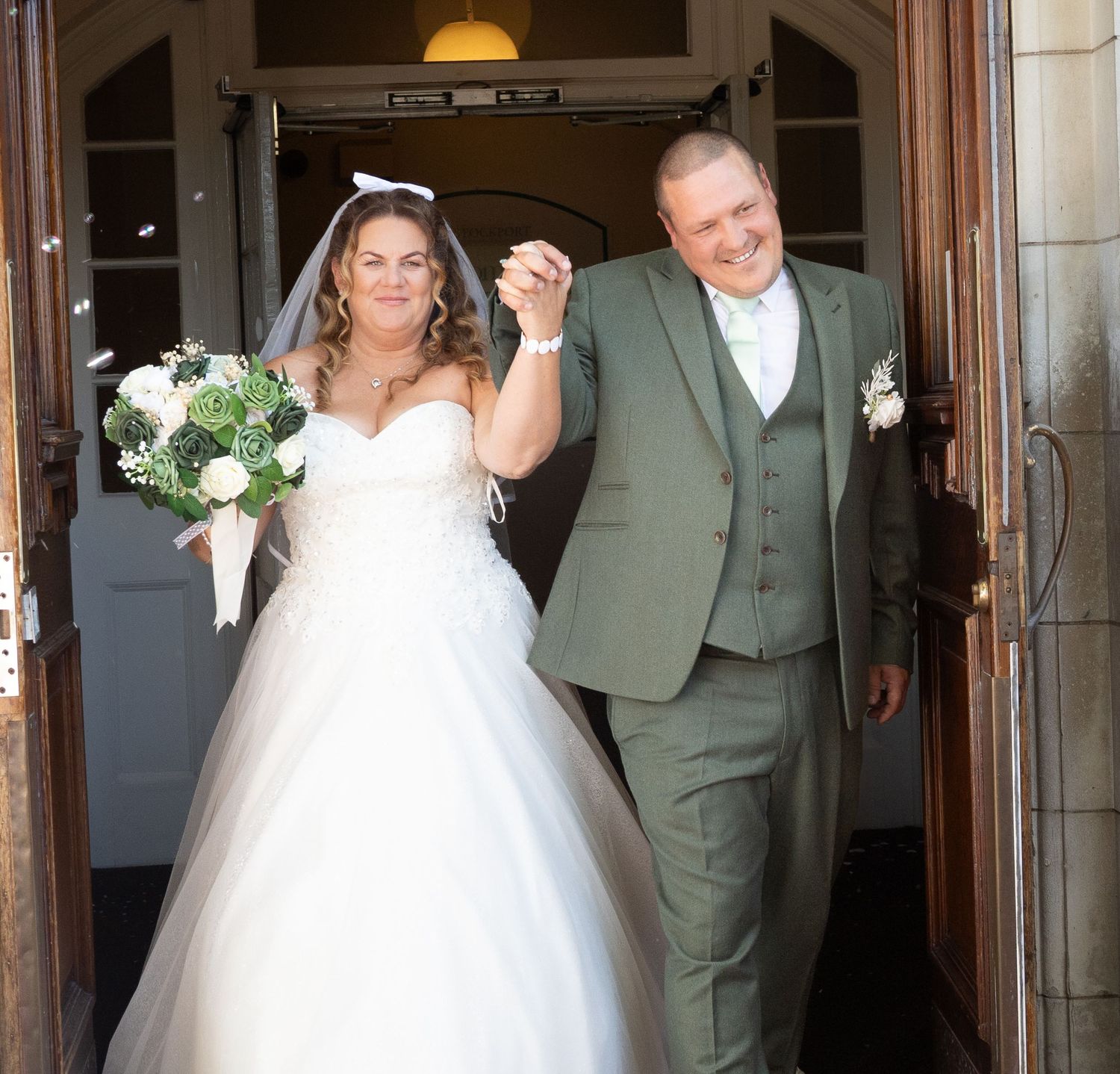 A bride and groom celebrate joyfully after their wedding ceremony in an elegant doorway setting.