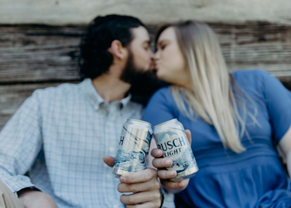 Couple sharing romantic moment while holding canned beverages.