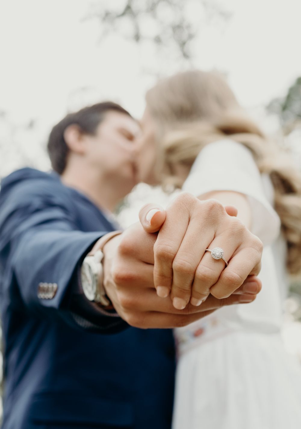 Close-up of hands showing engagement ring with soft focus background.