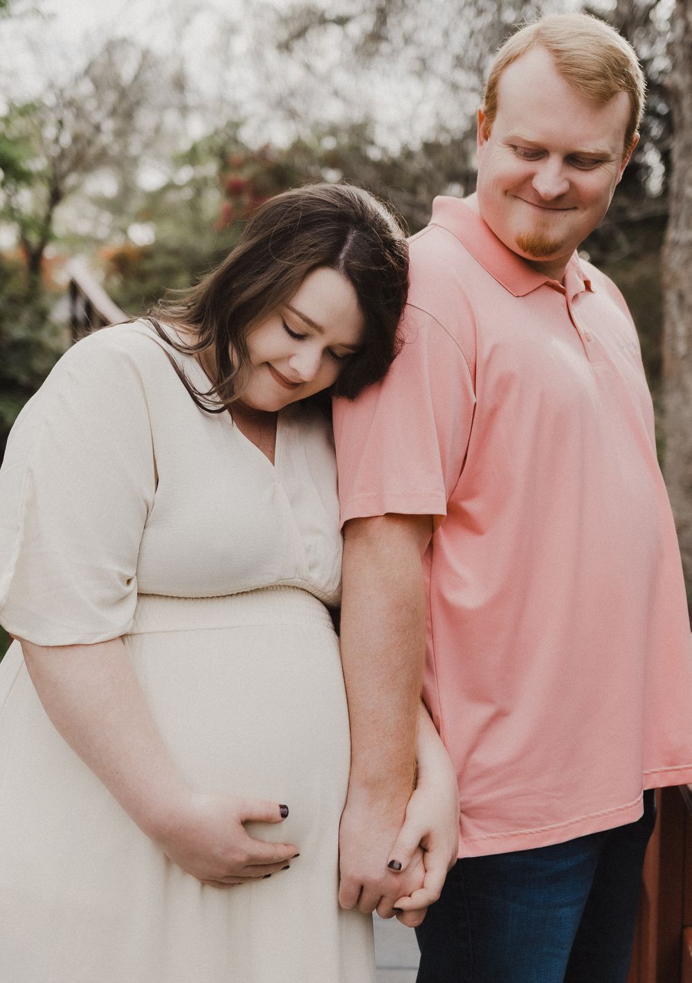 A couple shares tender moments together while wearing coordinating pink and cream colored outfits.