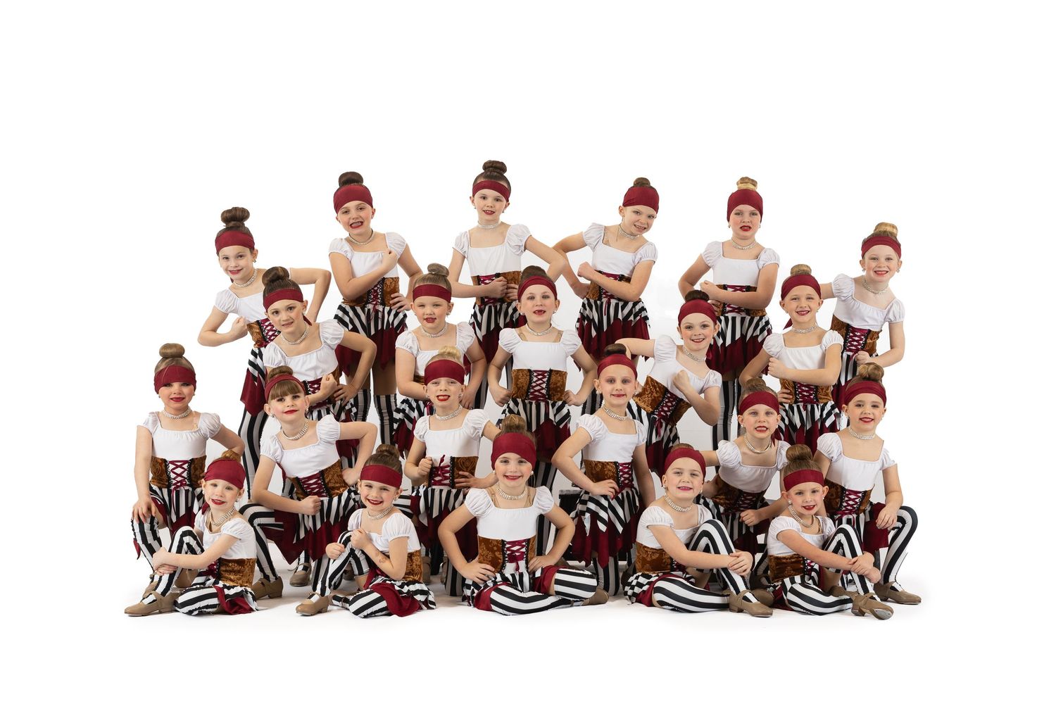 Group of dancers in matching black and white striped outfits pose together in synchronized formation on the floor.