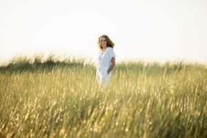 A person stands in a golden field of tall grass on a sunny day, creating a serene and peaceful scene.