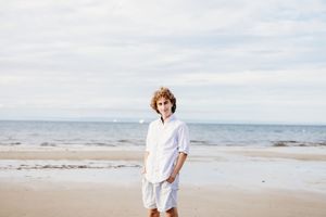 A series of connected beach photos showing someone in white clothing walking along the sandy shoreline at sunset.