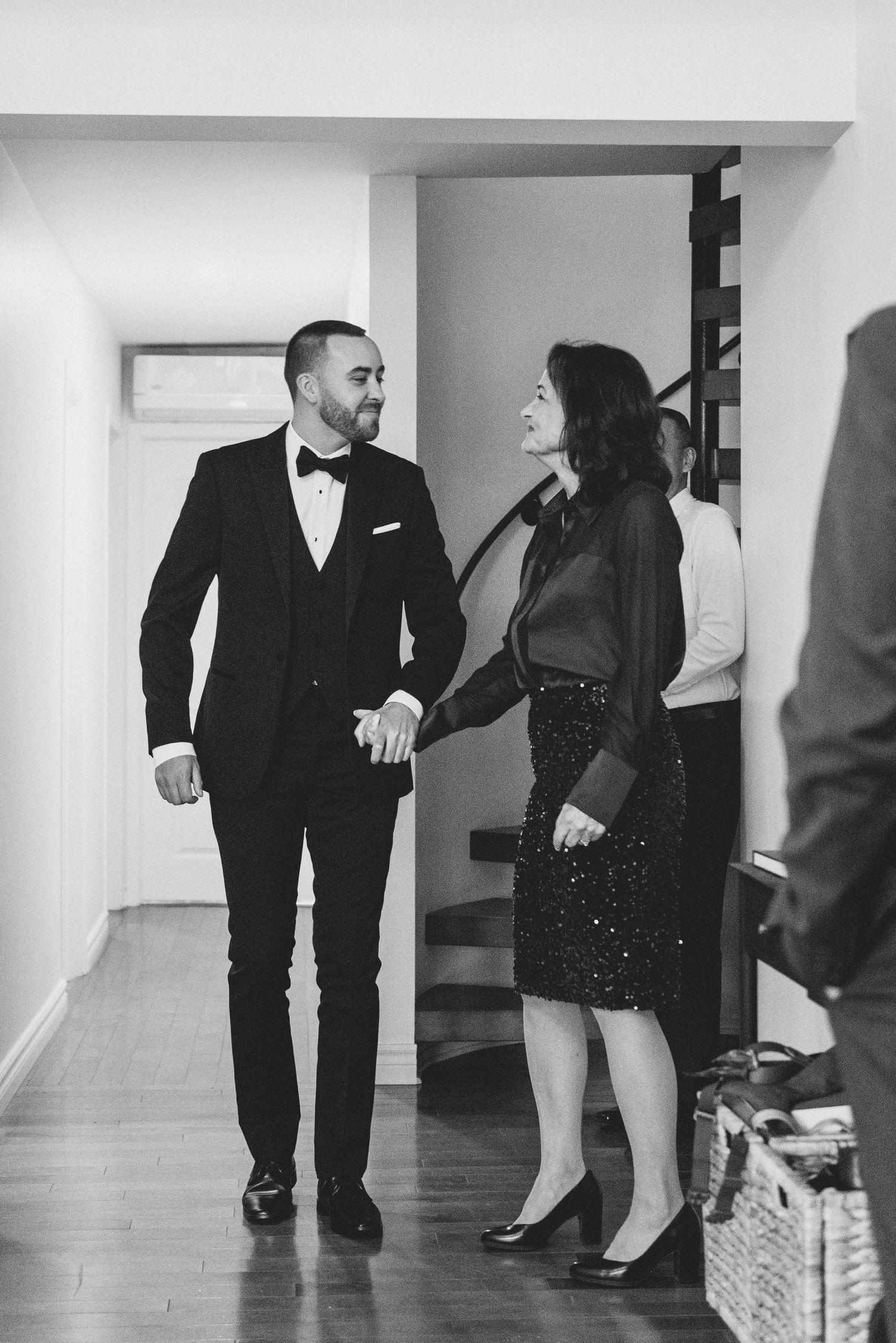 Black and white photo of a couple in formal attire walking together in a hallway.