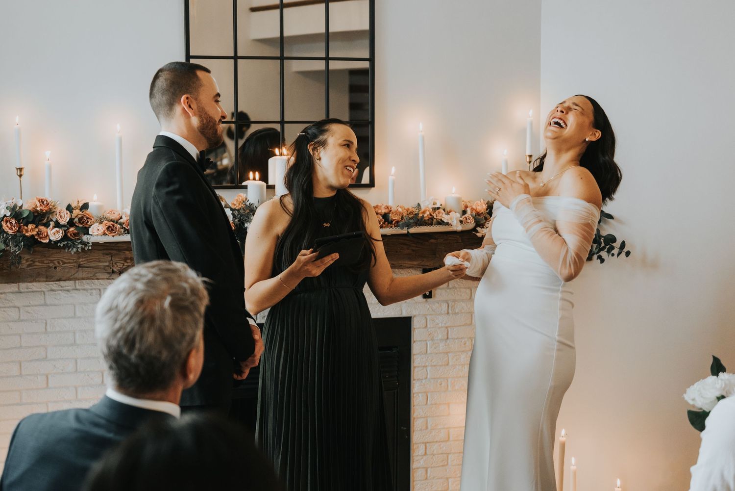 Candid moment of celebration during an indoor wedding ceremony with candlelit backdrop.