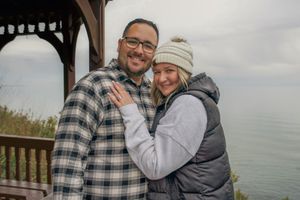 A couple shares tender moments in a series of outdoor photos by the ocean wearing casual winter clothing.