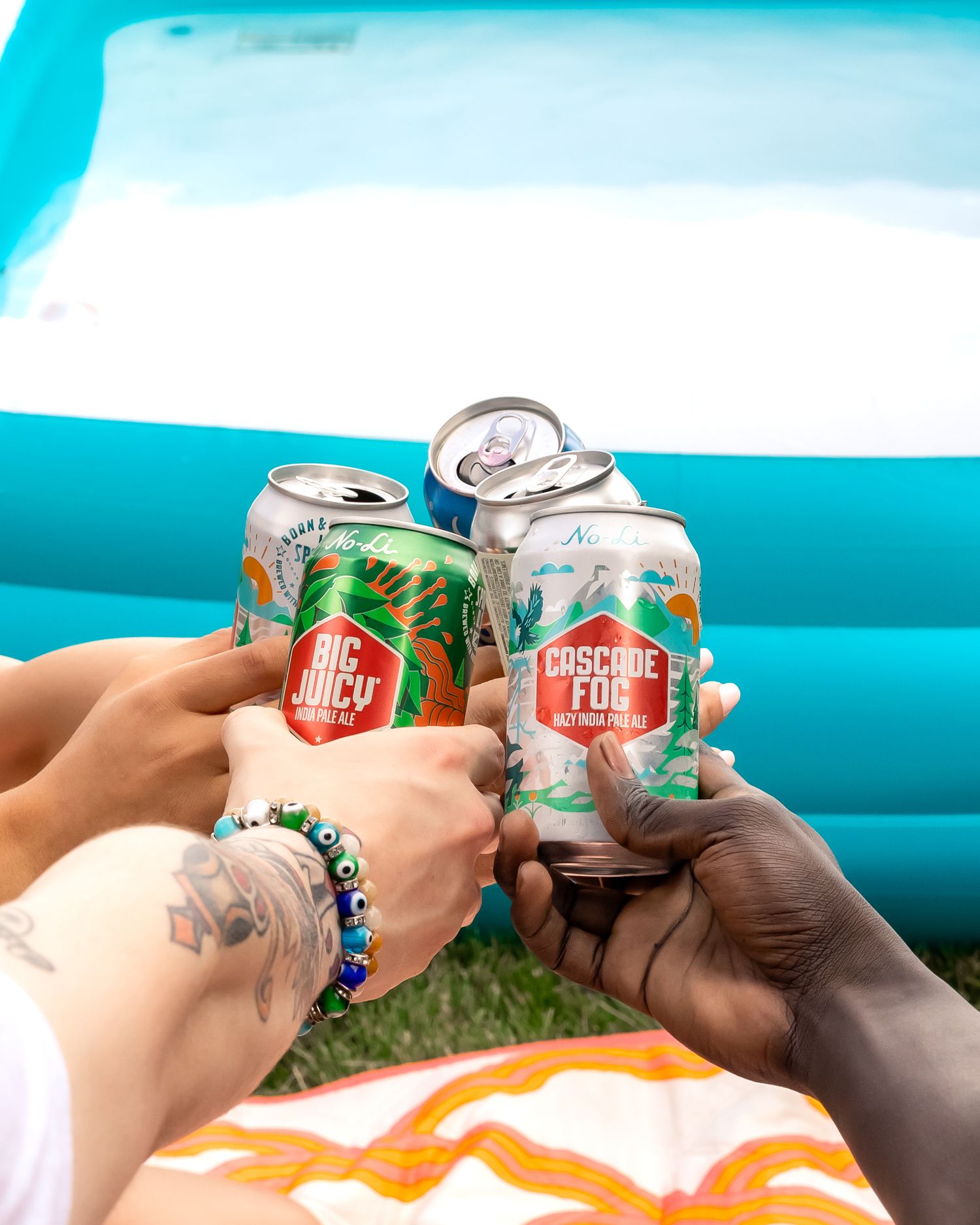 Friends toasting with cans of beer and soda against a bright turquoise background.