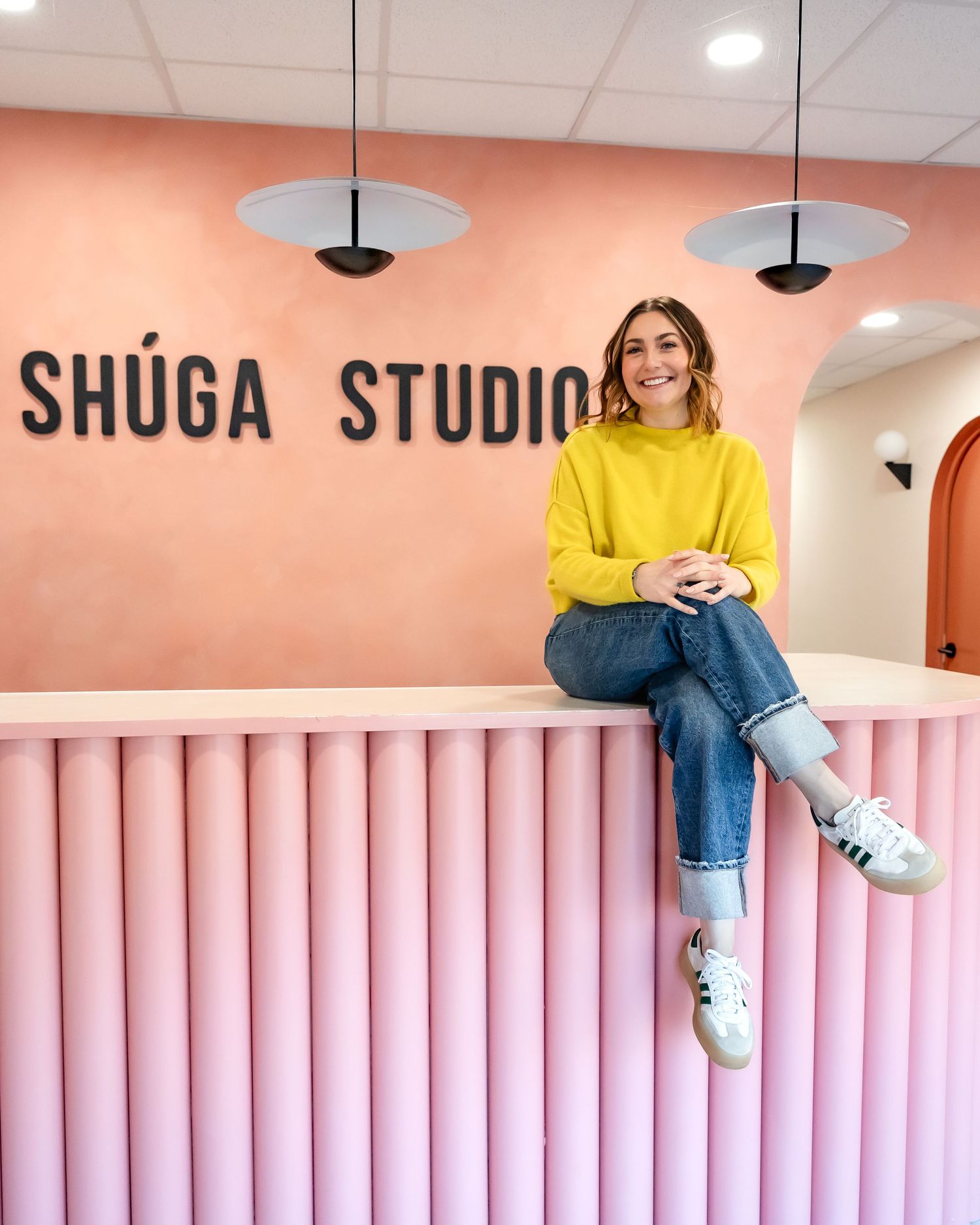 Pink-paneled studio interior with Shuga Studio signage and modern minimalist design elements.