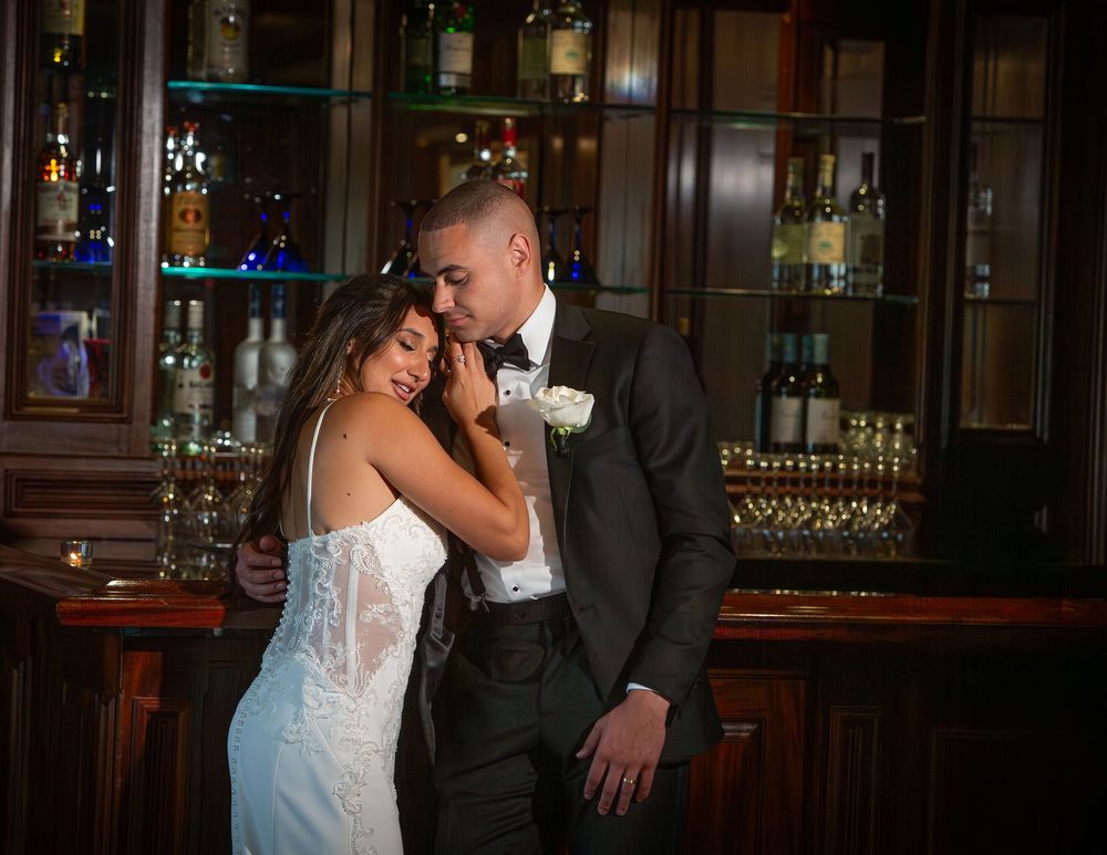 Elegant couple shares an intimate dance moment in a dimly lit ballroom with crystal chandeliers.