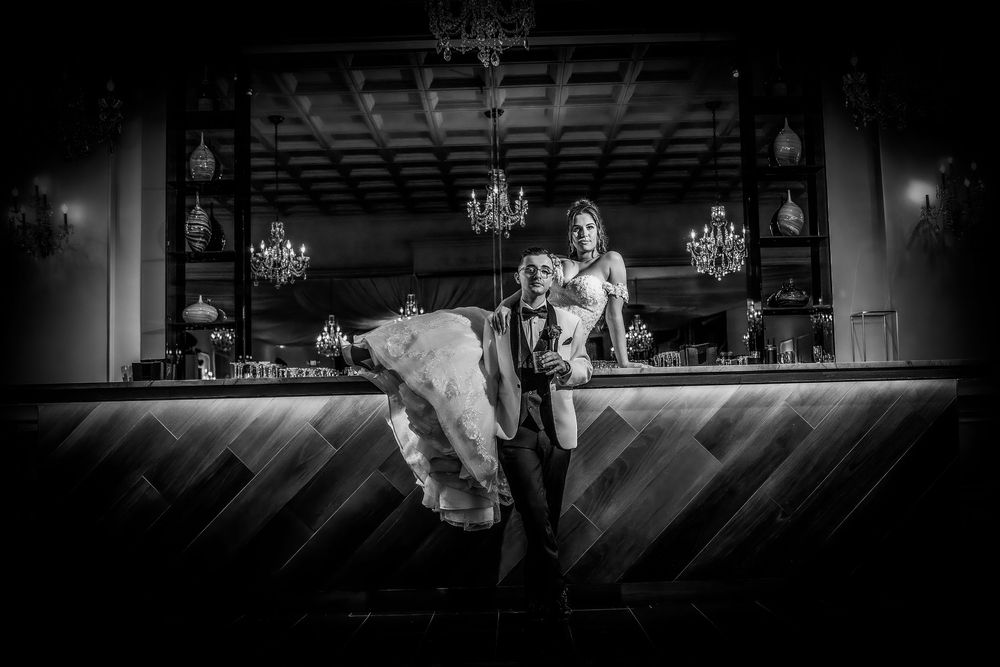 Black and white wedding reception photos showing elegant ballroom settings with chandeliers and dancing silhouettes.