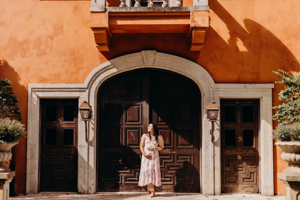 Orange-tinted architectural view of arched walkways and columns along a Mediterranean-style building facade.