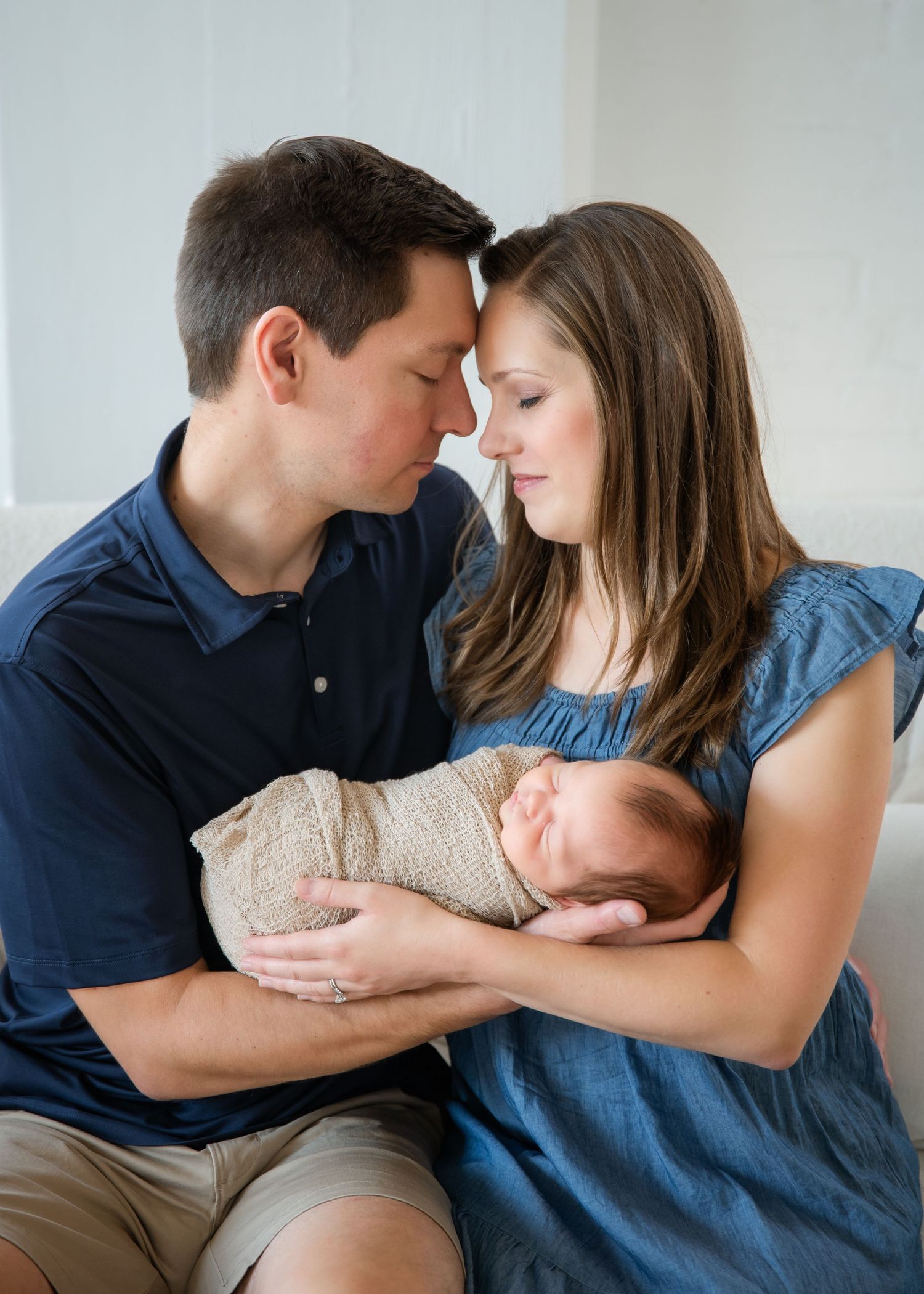 A person sits on a white couch while embracing a small child in a playful sequence of candid moments.