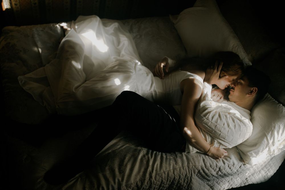 Artistic boudoir sequence with dramatic shadows and white bedding.