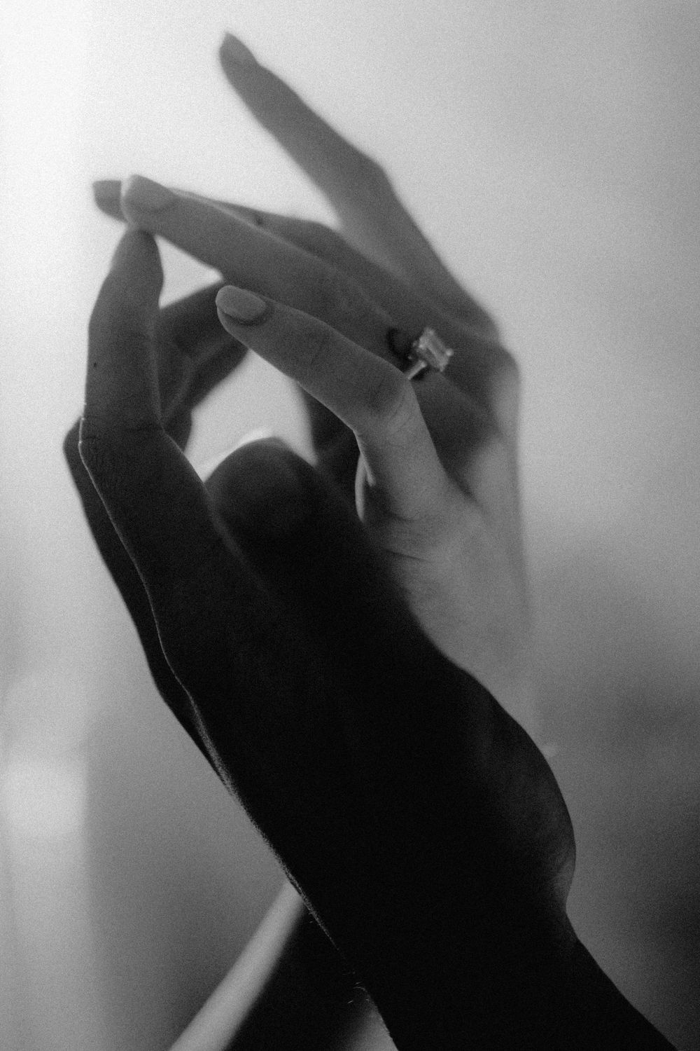 Silhouetted hands reach upward against a bright, diffused background.