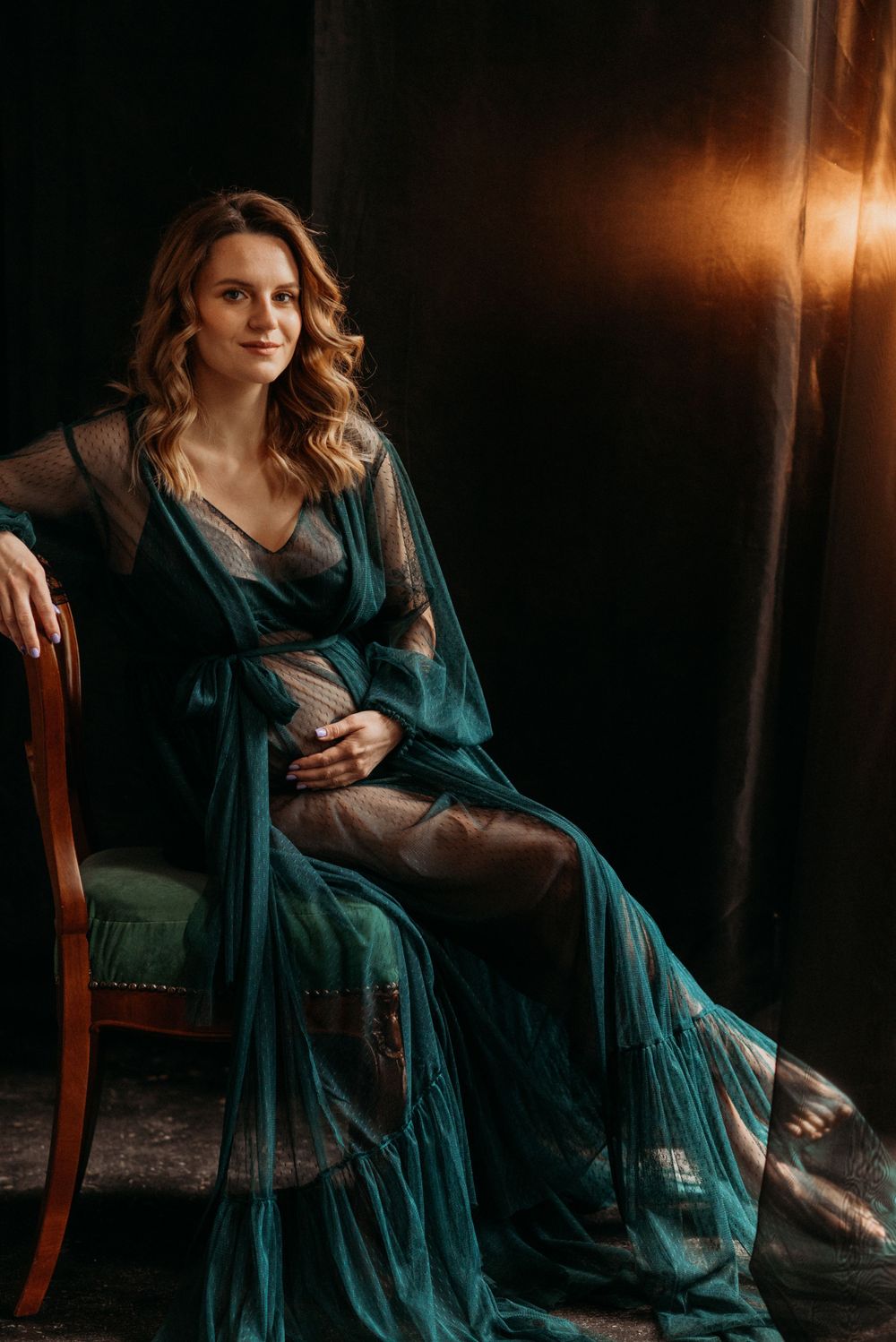 Intimate portrait session with a teal dress in dramatic low-key lighting.