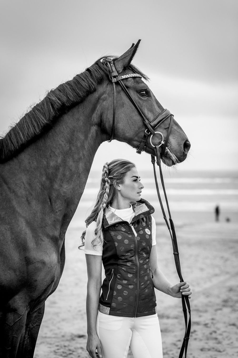 A black and white portrait of a horse and rider on a misty beach.