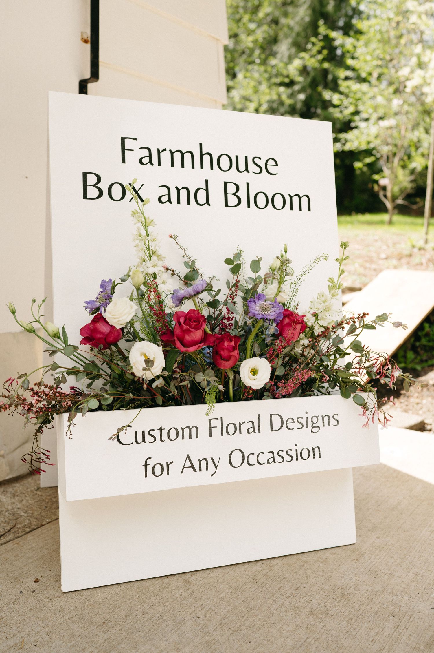 Farmhouse Box and Bloom business sign with colorful floral arrangement display.