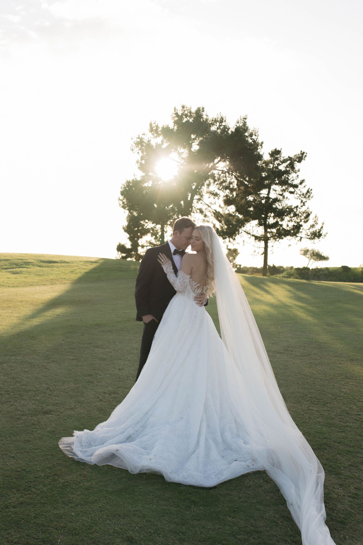 A romantic moment between newlyweds against white curtains at their wedding reception.