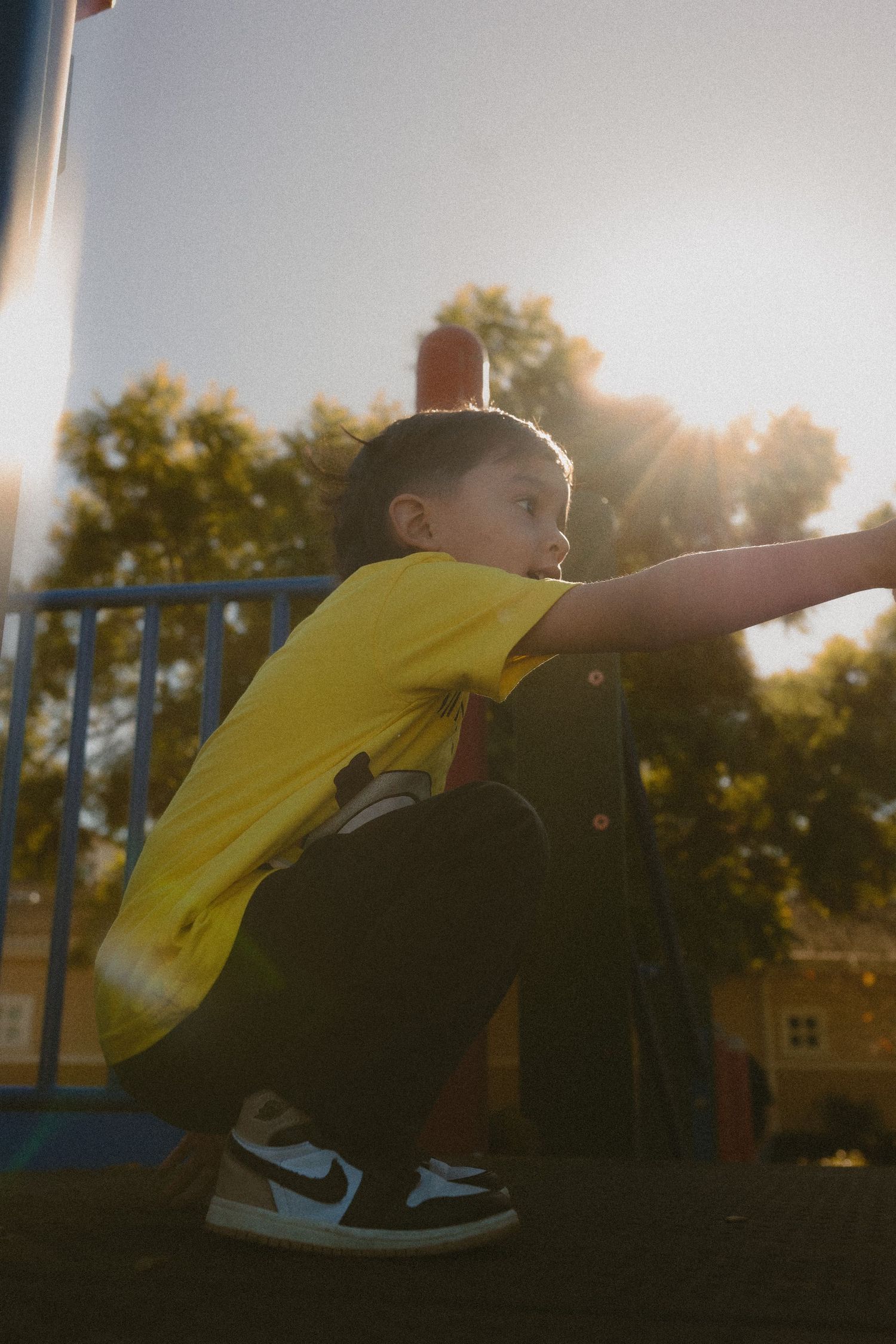 Child in yellow shirt playing outdoors at sunset, leaning forward with determination.