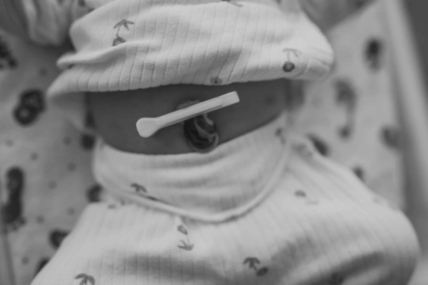 Black and white close up photograph of a person wearing a light colored cap and face covering.