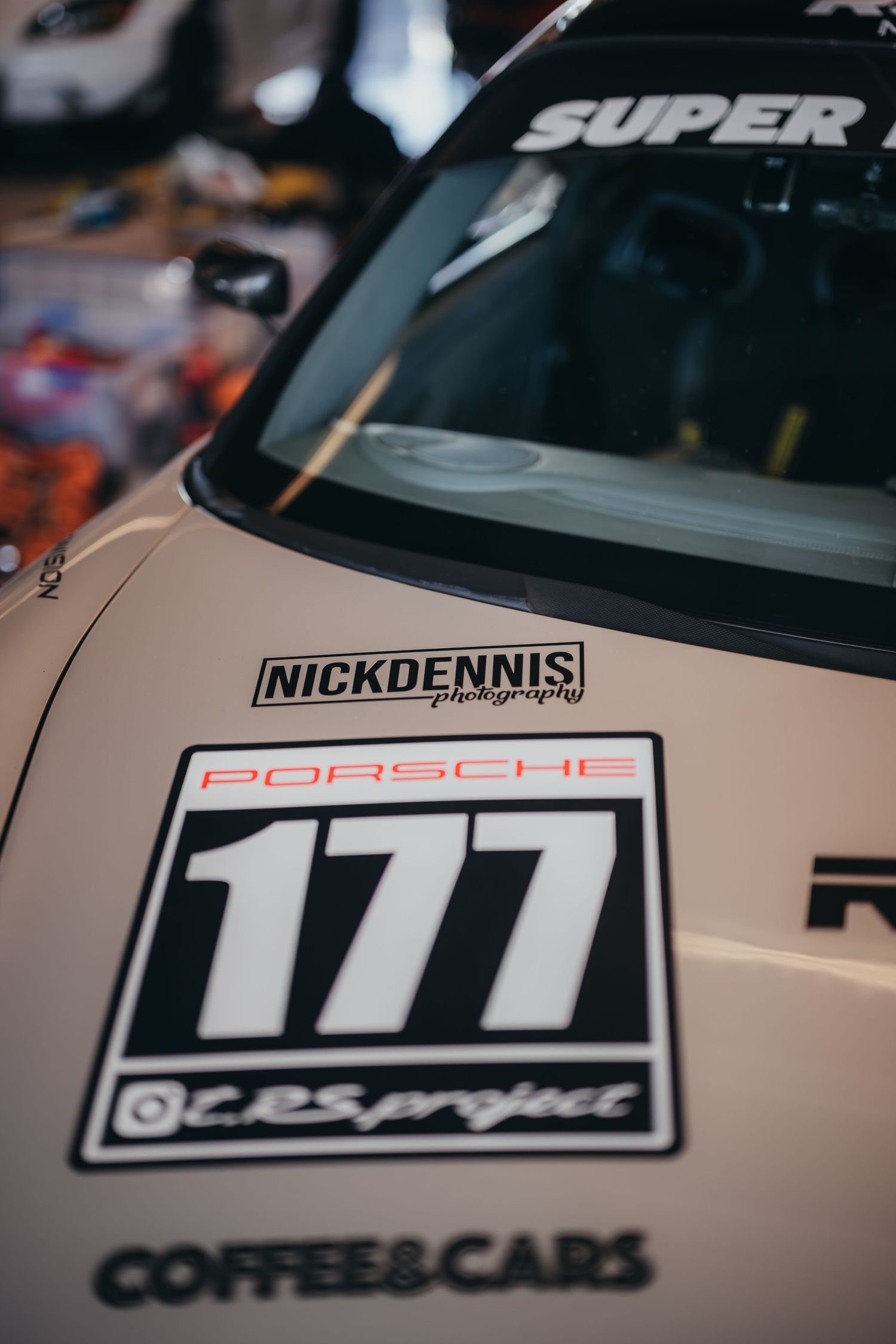 Close-up detail of a white Porsche race car showing number 171 and sponsorship decals.