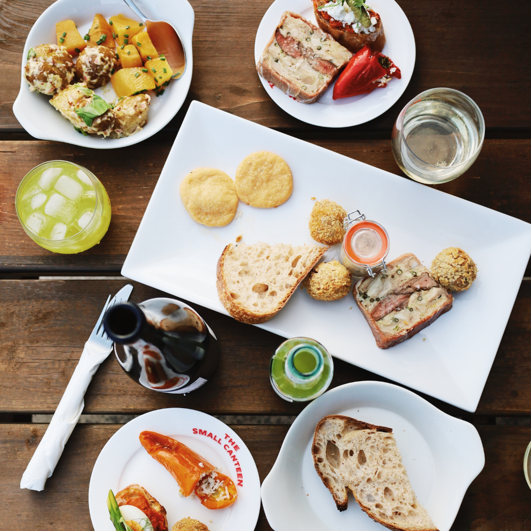 Various gourmet dishes and appetizers served on white plates on a wooden table.