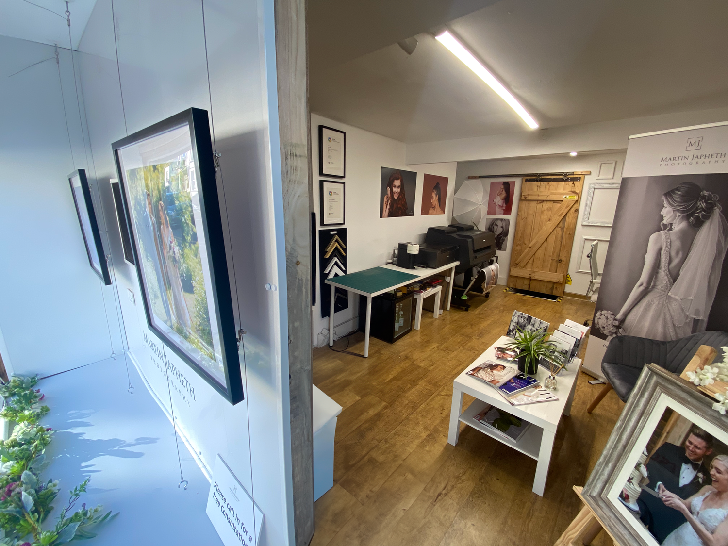A cozy home office or studio space with artwork on walls, a white coffee table, and wooden flooring.