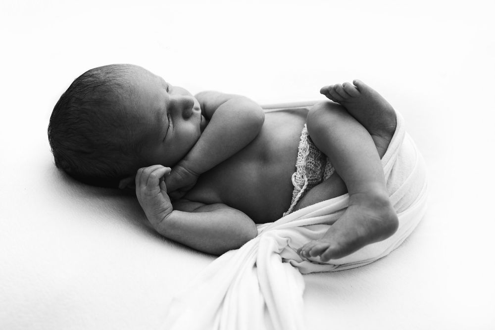 Black and white artistic photo series showing a sleeping newborn baby in different poses.