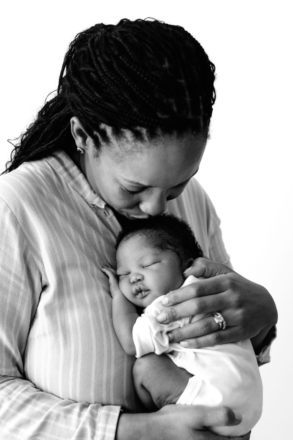 A heartwarming black and white portrait showing a tender moment between a parent and sleeping baby.