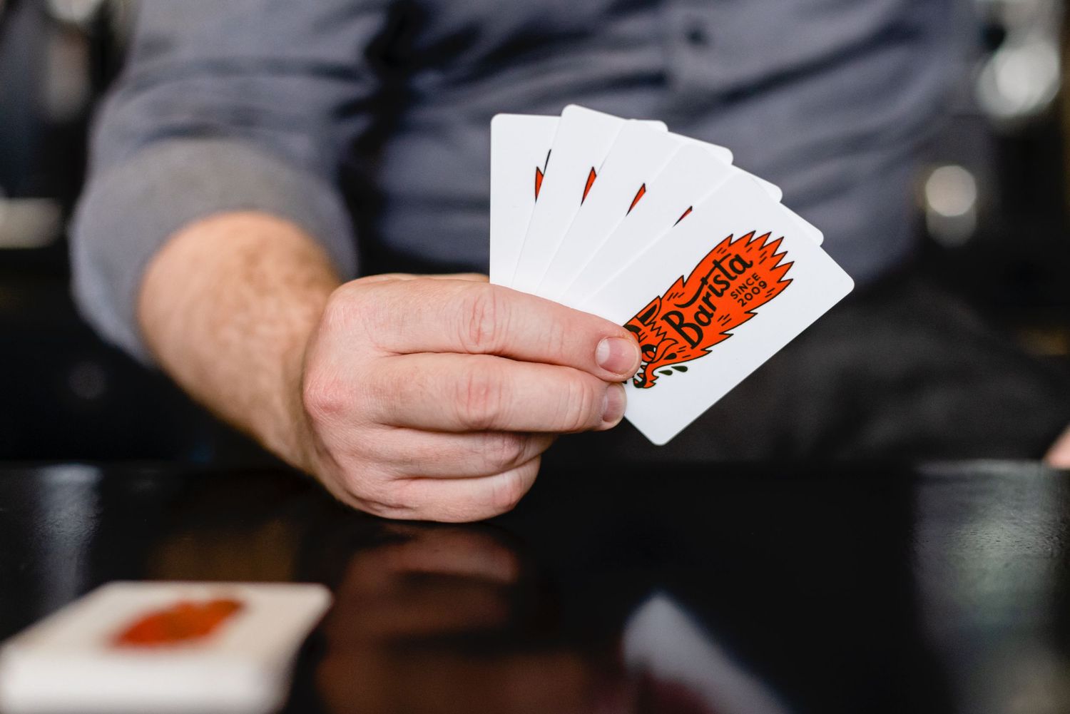 Hands holding playing cards with red text against a dark background during a card game.