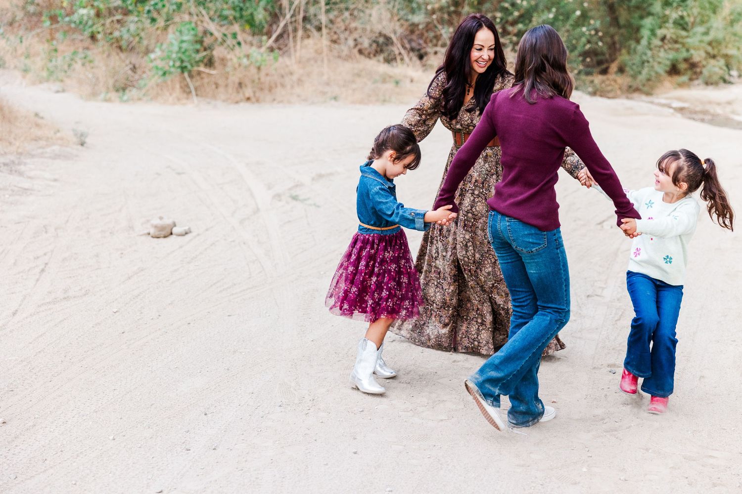 People dancing together on a photoshoot on a dirt path in Simi Valley wearing colorful casual clothing and flowy dresses.