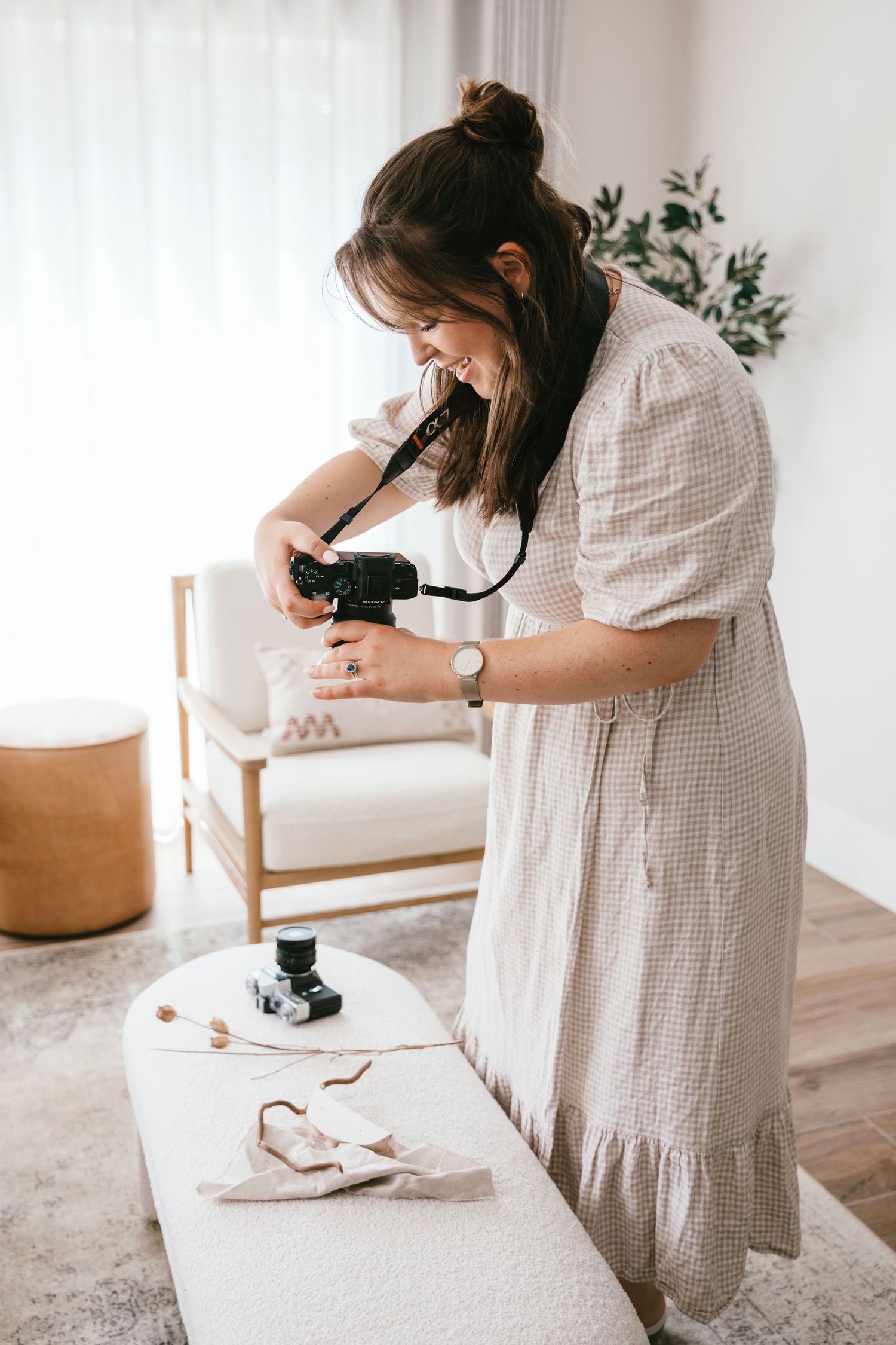 Portrait of photographer Katie Rhona Photography wearing gingham dress and taking product photo.