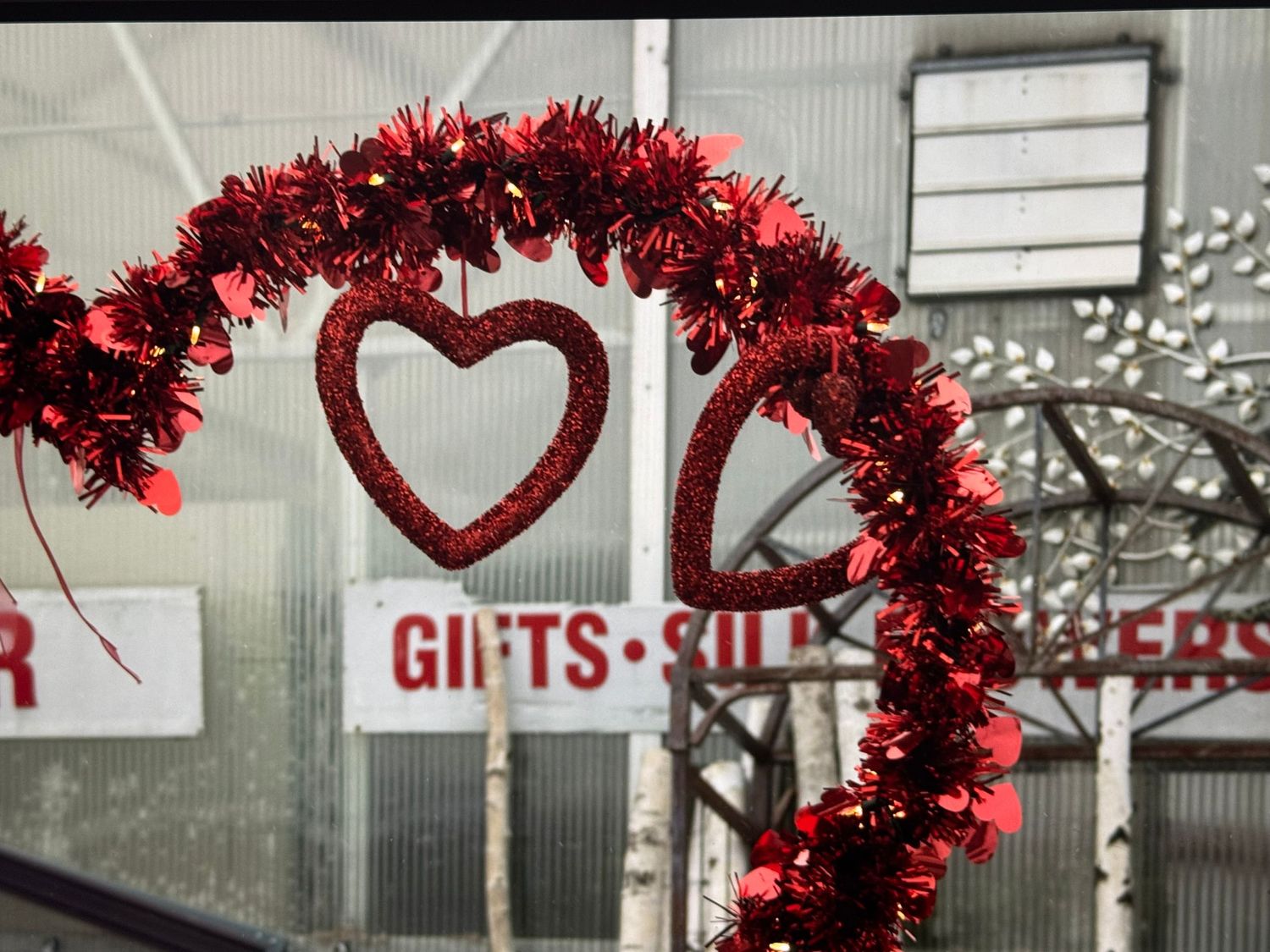 Red tinsel heart-shaped Valentine's decoration hanging in front of a retail store window.