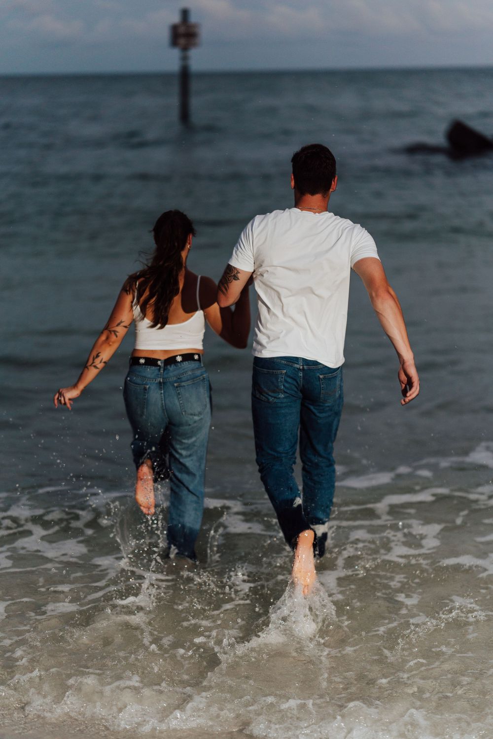 A couple wearing jeans posing for engagement photoshoot by the beach with direct flash photography in St. Pete Florida
