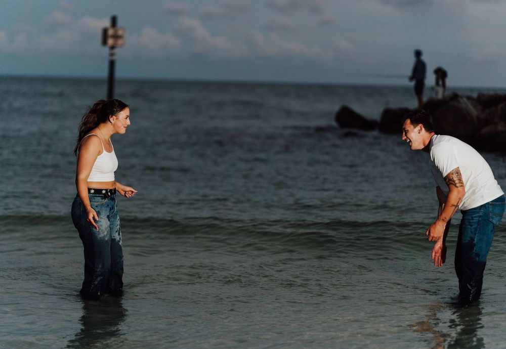 A couple wearing jeans posing for engagement photoshoot by the beach with direct flash photography in St. Pete Florida