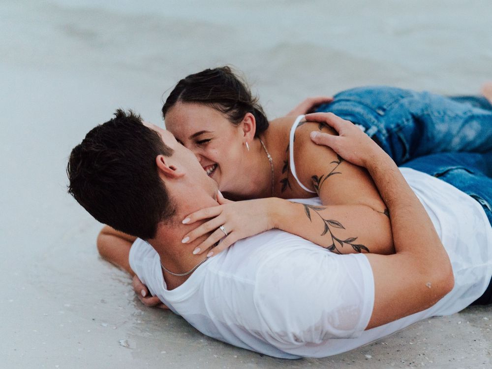 A couple wearing jeans posing for engagement photoshoot by the beach with direct flash photography in St. Pete Florida