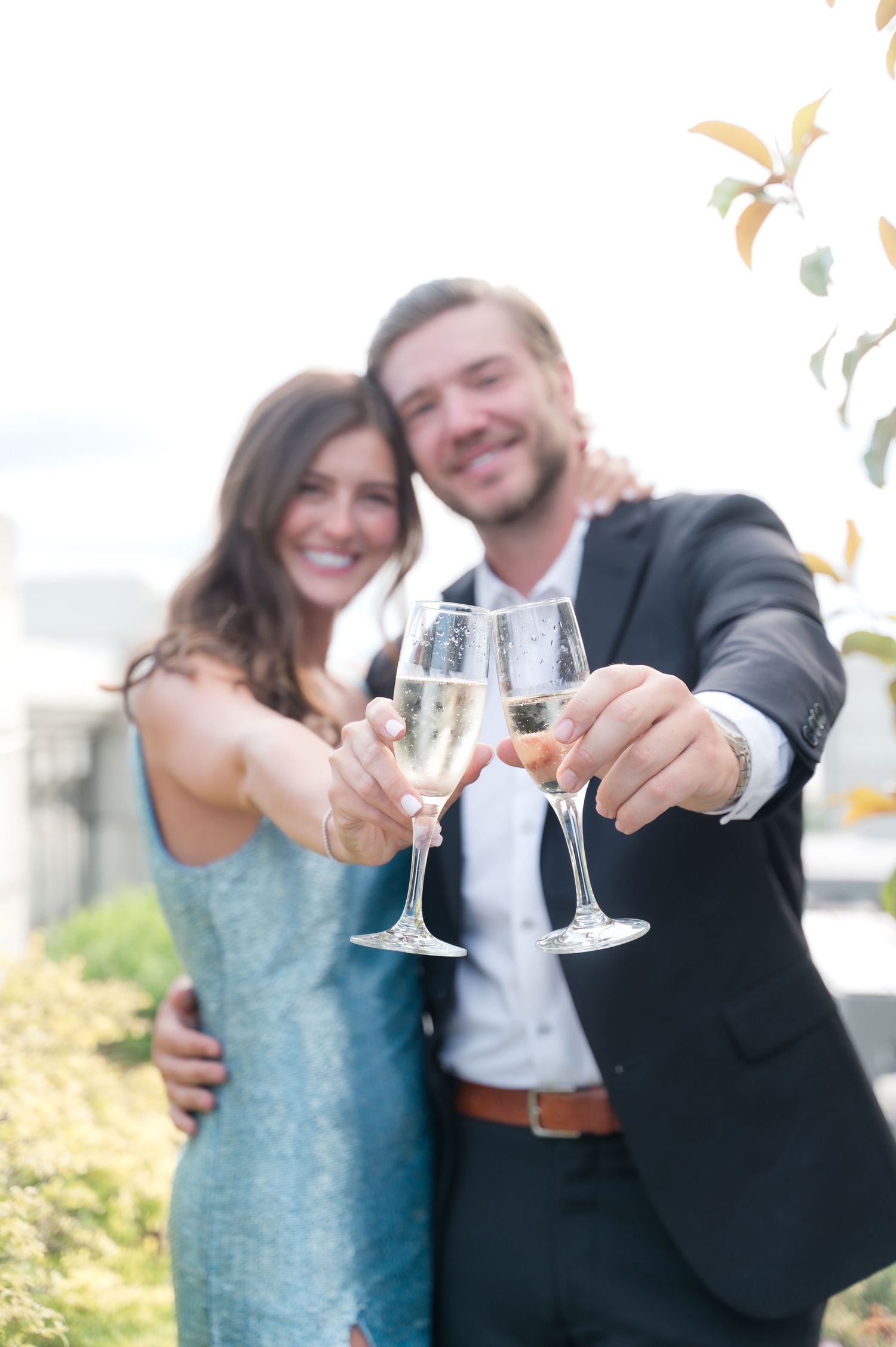 A couple in formal attire toasting with champagne glasses at an their rehearsal dinner.