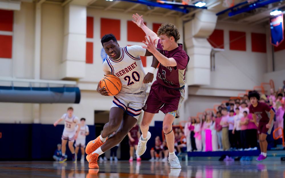 Manheim Central defender jumps to block a Trojans player driving to the basket by SportsFox Photography, Hershey PA.